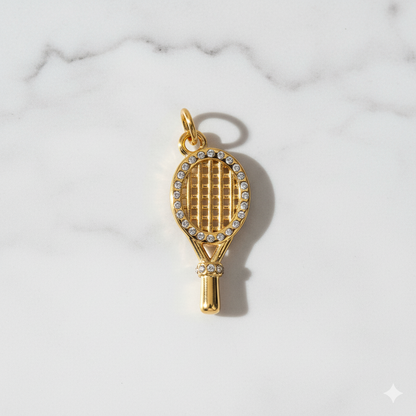 Gold tennis racket charm with rhinestones on a marble background