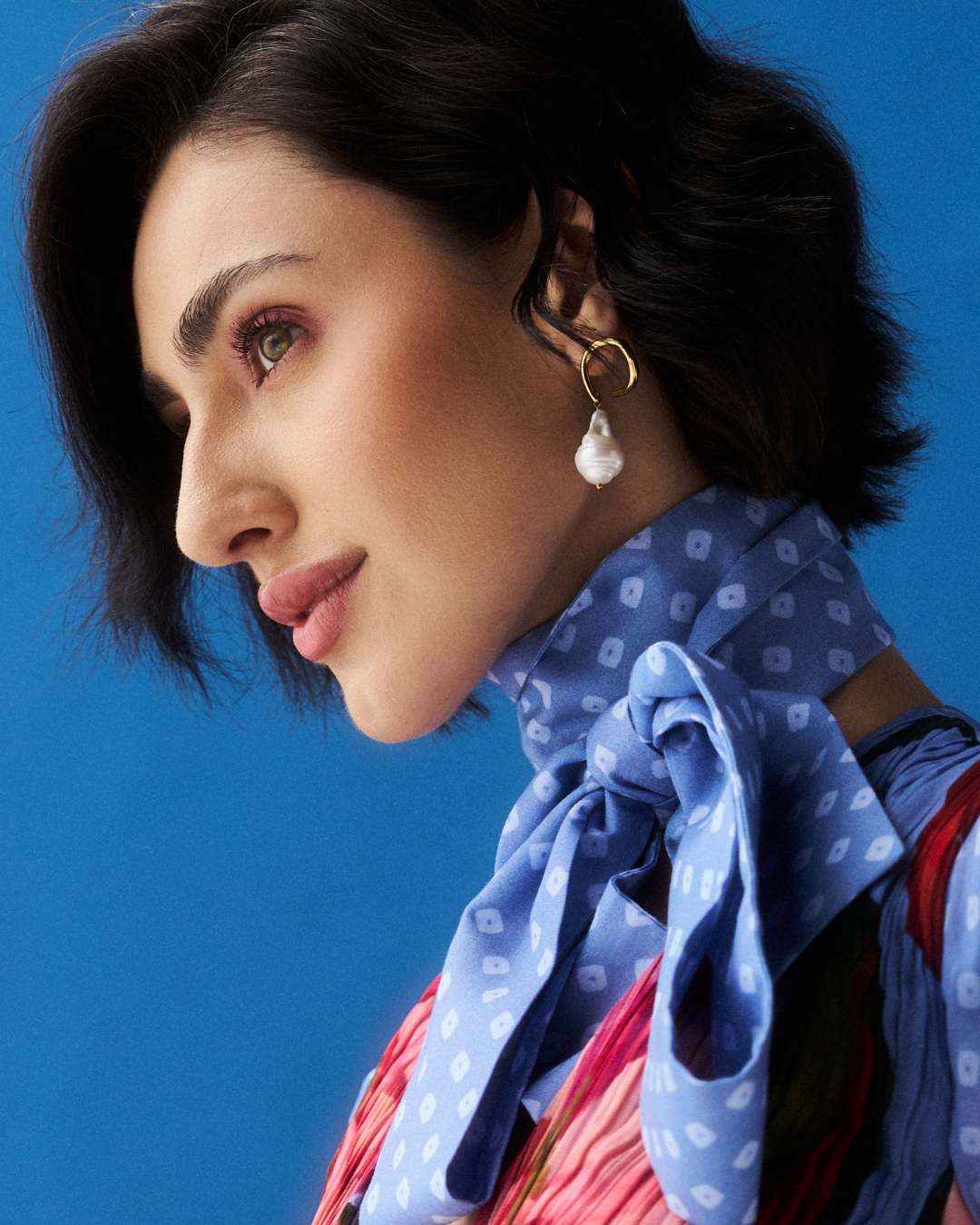 Woman wearing a blue polka dot scarf against a blue background