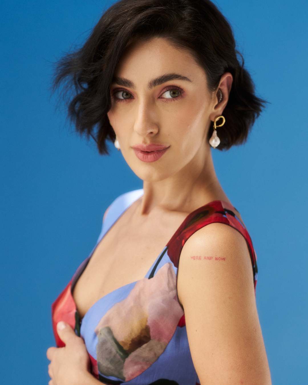 Woman with a tattoo on her arm against a blue background