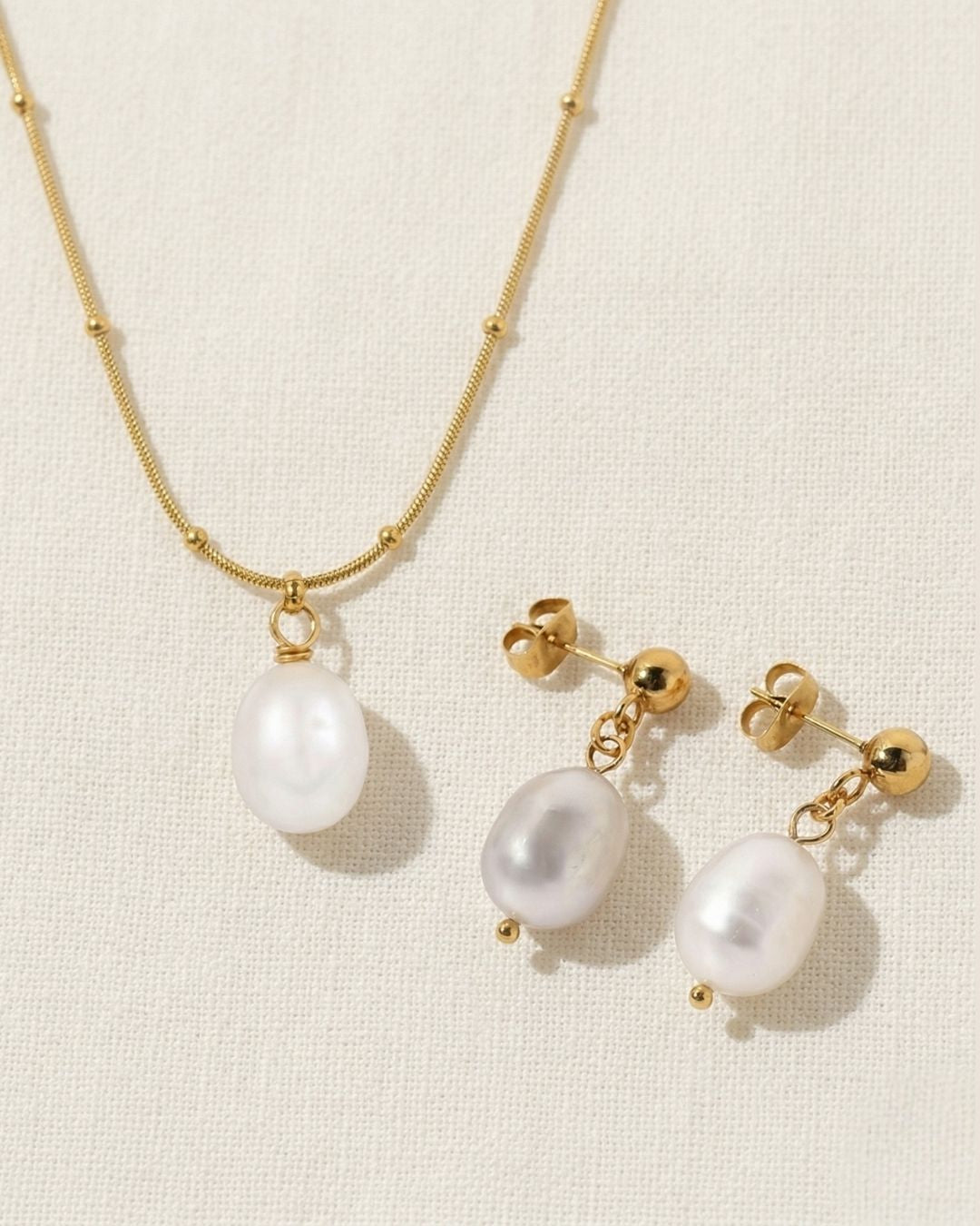 Pearl necklace and earrings set on a beige background