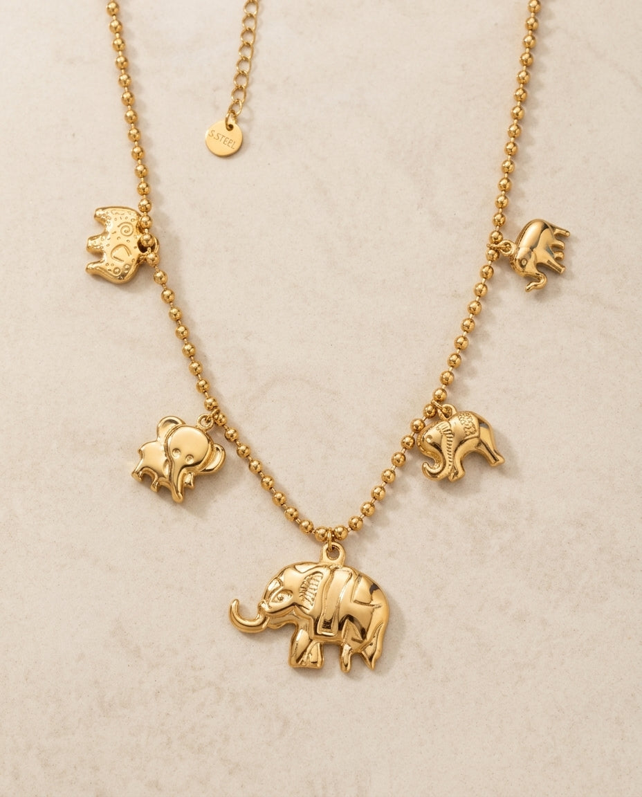 Gold necklace with elephant pendants on a beige background