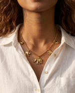 Gold elephant necklace worn by a person with a white shirt
