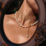 Pearl necklace with a gold chain worn by a person, close-up view.
