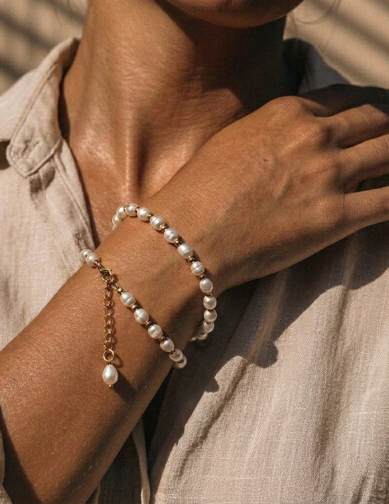 Person wearing a pearl bracelet on a neutral background