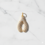 Gold and diamond teardrop pendant on a marble background