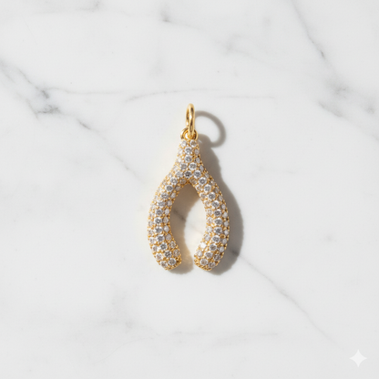 Gold and diamond teardrop pendant on a marble background