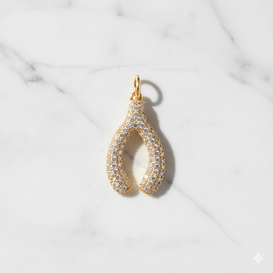 Gold and diamond teardrop pendant on a marble background