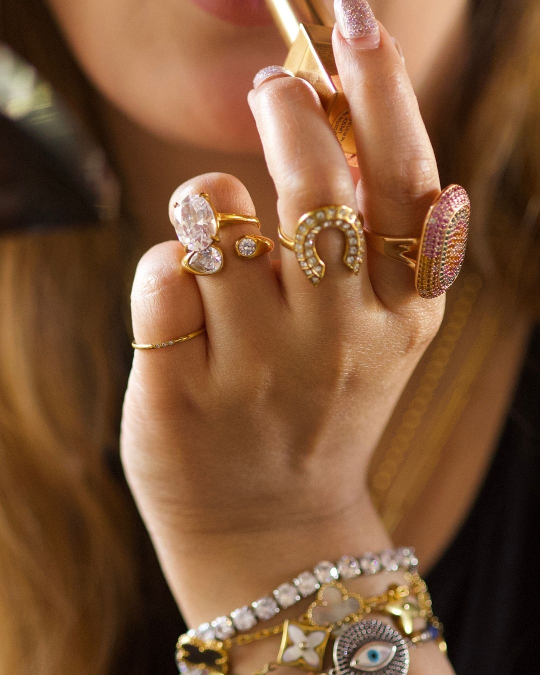 Close-up of a hand wearing multiple gold rings with gemstones.