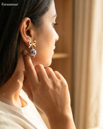 Woman wearing a decorative earring with a bow design, indoors.