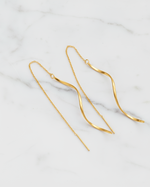 Gold chain earrings on a light marble background