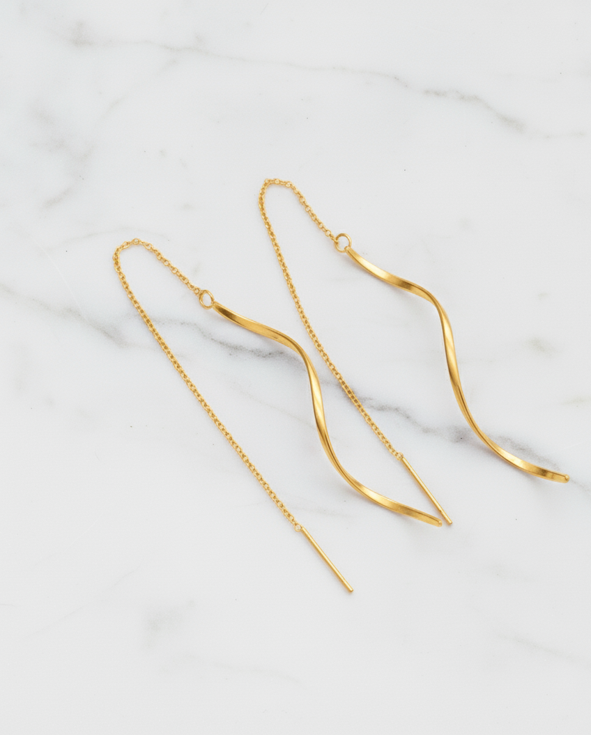 Gold chain earrings on a light marble background