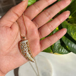 Hand holding a necklace with a decorative pendant against a blurred background