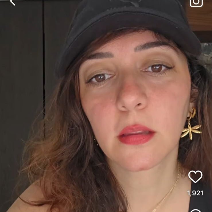 Person wearing a black cap and black top with visible branding, on a smartphone screen interface.