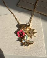 Necklace with floral and butterfly charms on a textured surface