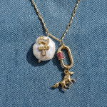 Necklace with a pearl pendant and horse charm on a denim background