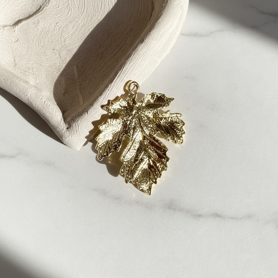 Gold leaf-shaped pendant on a marble surface