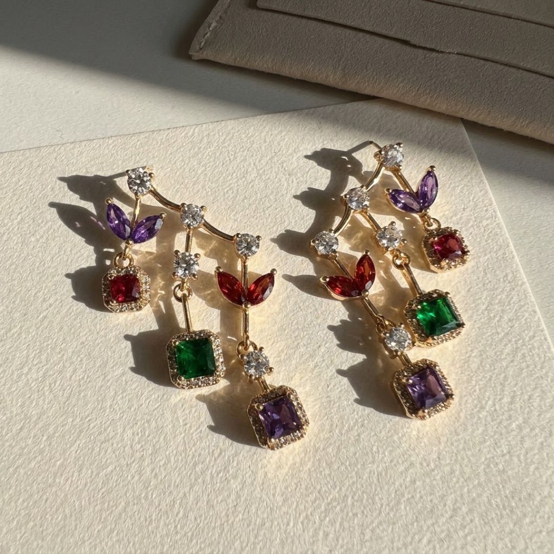 Long gold drop earrings with purple, red, emerald and amethyst halo stones stacked vertically shot on sunlight