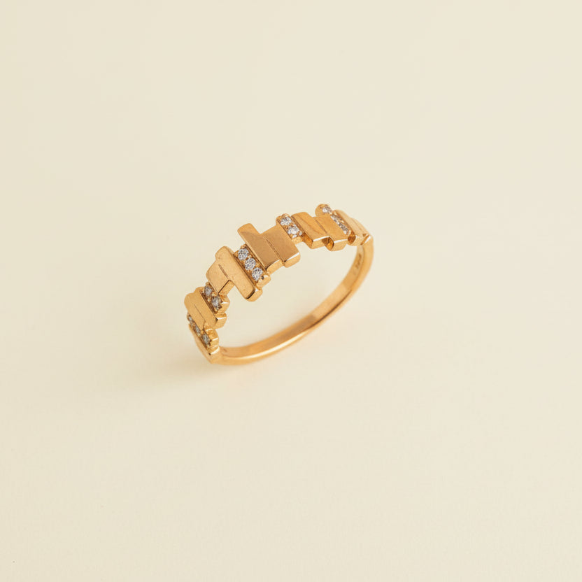 Gold ring with a unique design on a light gray background