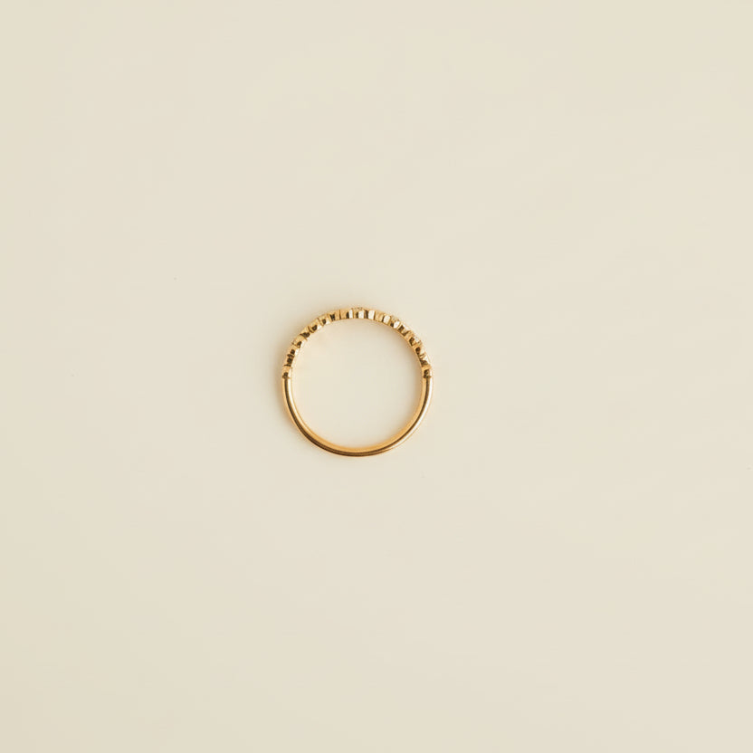 Rose Gold ring on a light gray surface with a beige textured object partially visible.