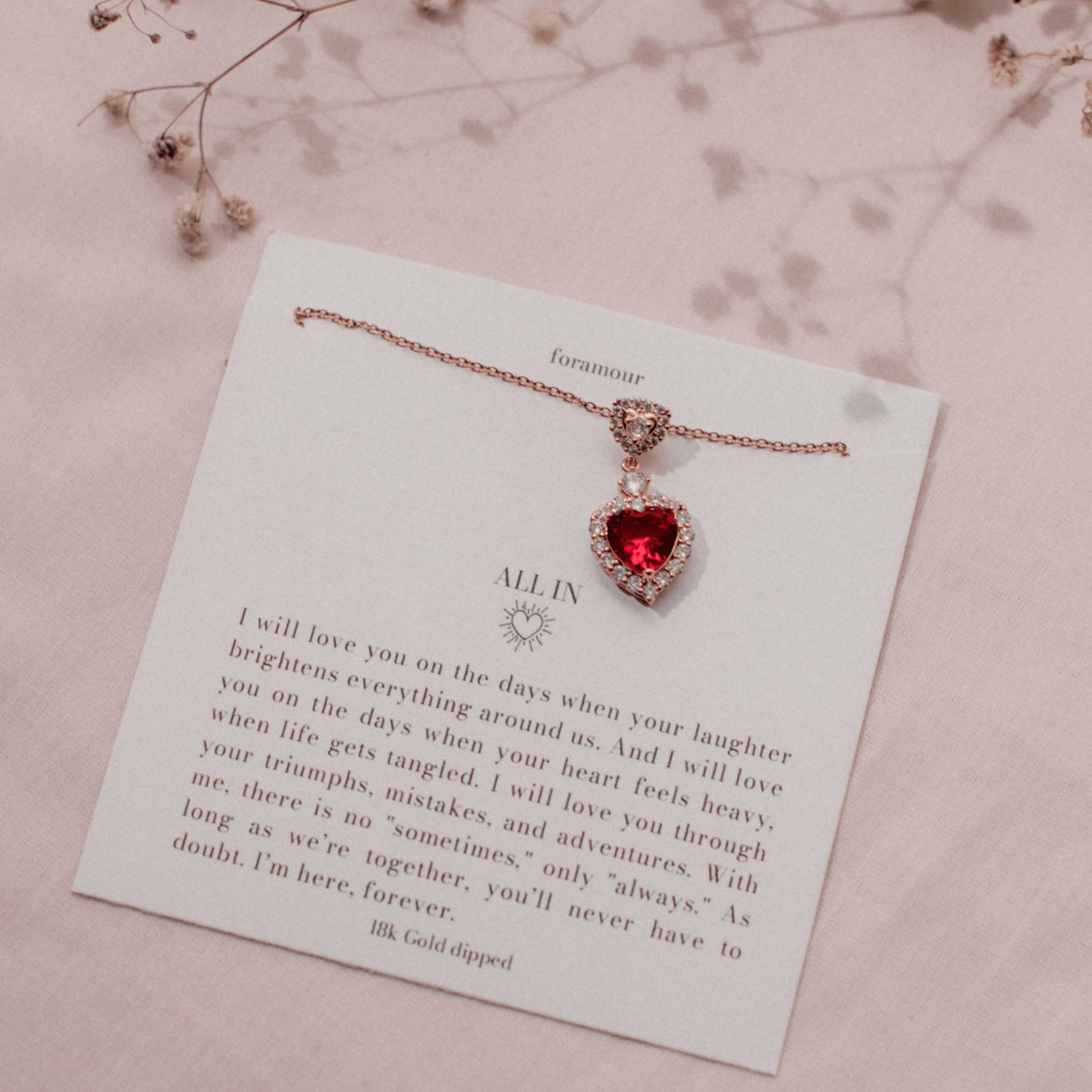 An elegant heart-shaped ruby pendant necklace with crystal accents, displayed on a card that reads 'Alain', suggesting a personal touch.