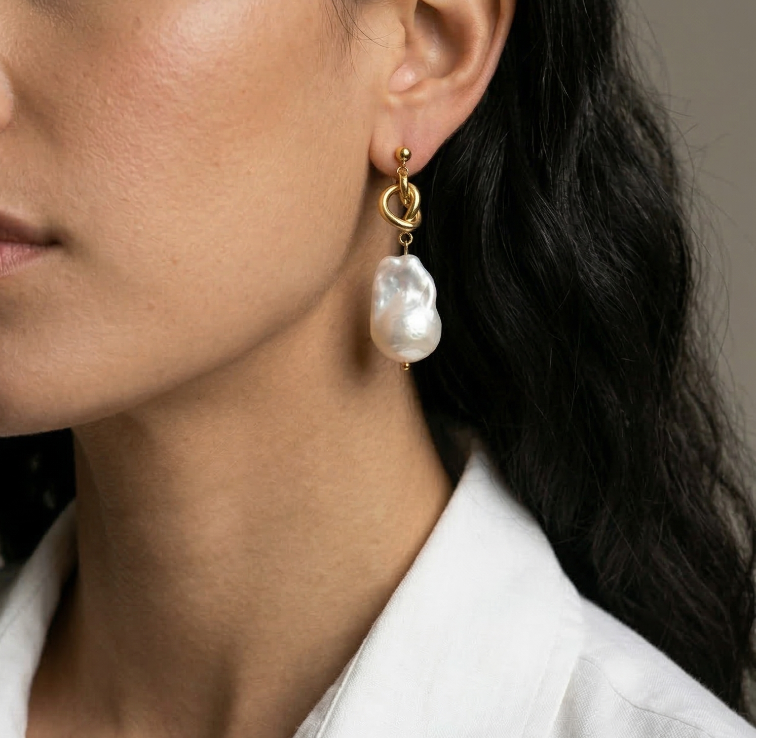 Woman wearing a pearl earring with a neutral background