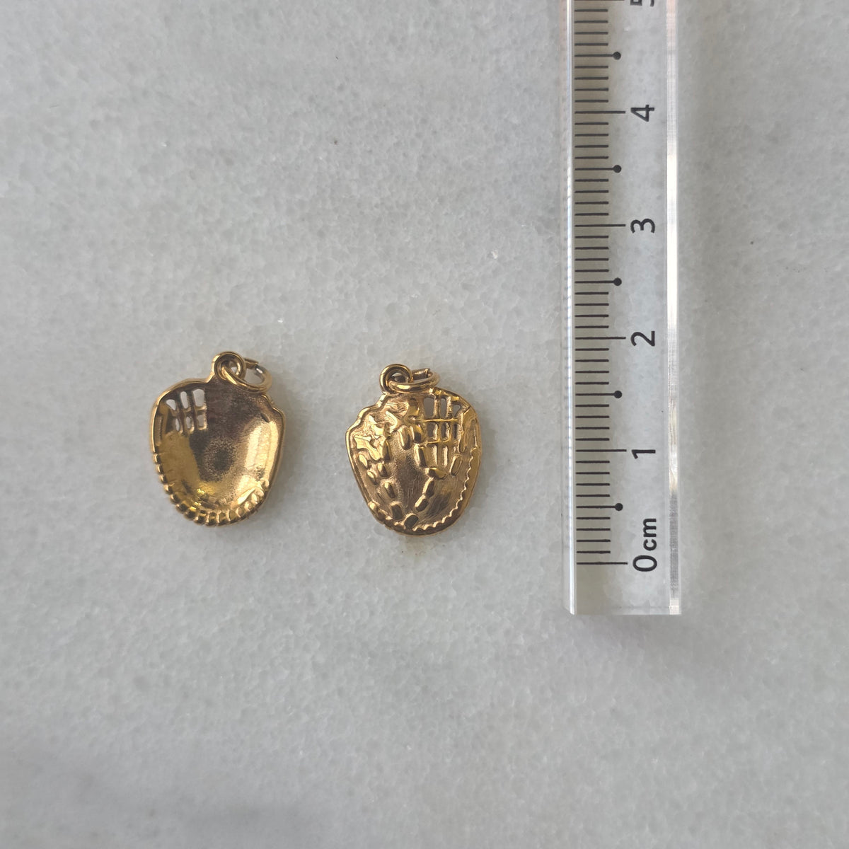 Gold baseball glove charm on a marble surface