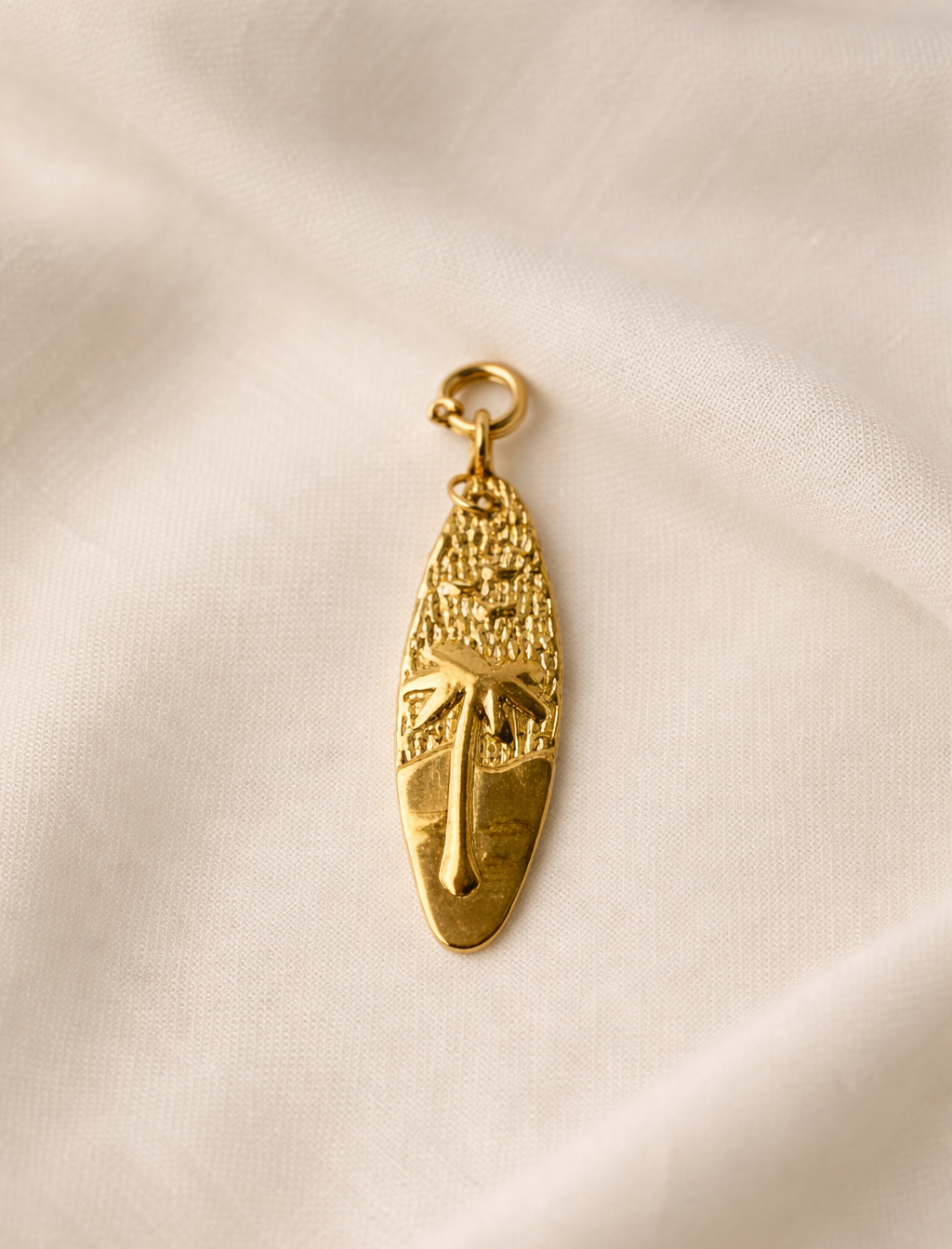 Gold pendant on a beige fabric background
