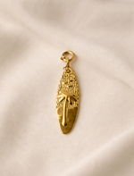 Gold pendant on a beige fabric background