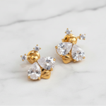 Gold earrings with clear gemstones on a light gray background