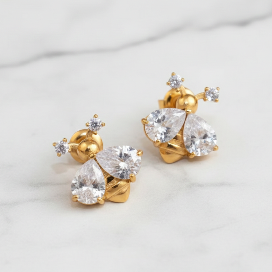 Gold earrings with clear gemstones on a light gray background