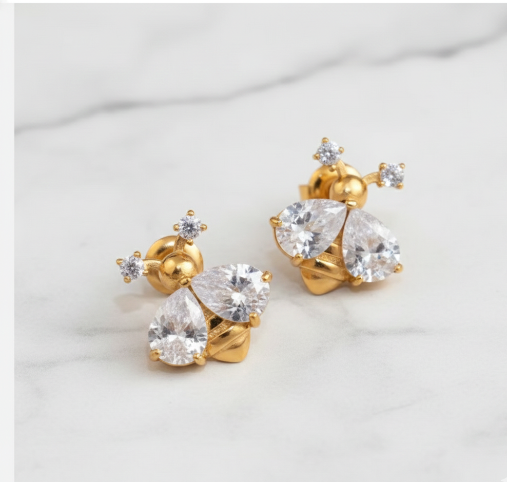 Gold earrings with clear gemstones on a light gray background