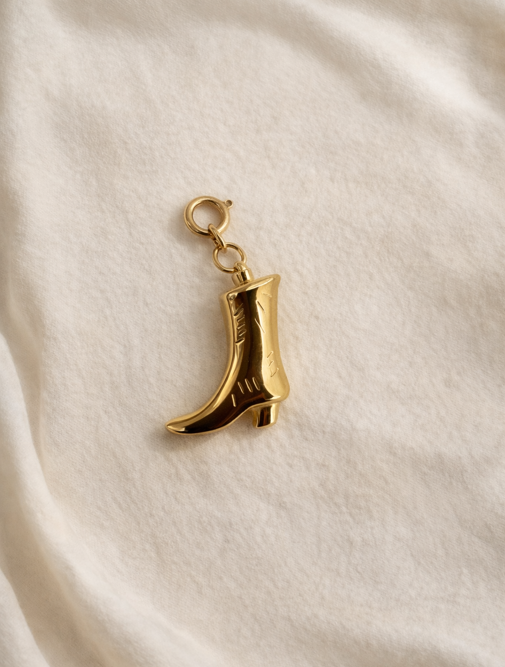 Gold boot-shaped charm on a beige fabric background