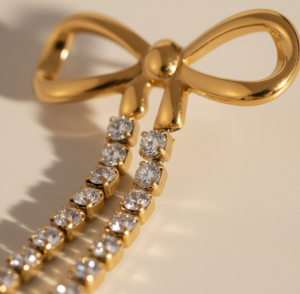 Gold bow-shaped earring with diamond accents on a beige background