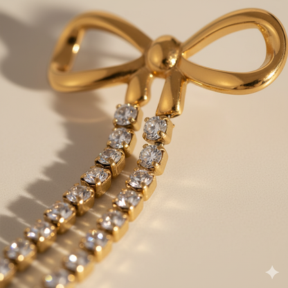 Gold bow-shaped earring with diamond accents on a beige background