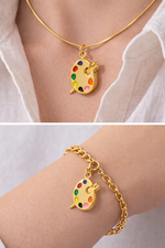 Gold necklace with a colorful palette pendant on a white shirt, followed by a gold bracelet with the same pendant on a wrist.