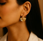 Close-up of a woman wearing gold earrings with a neutral background