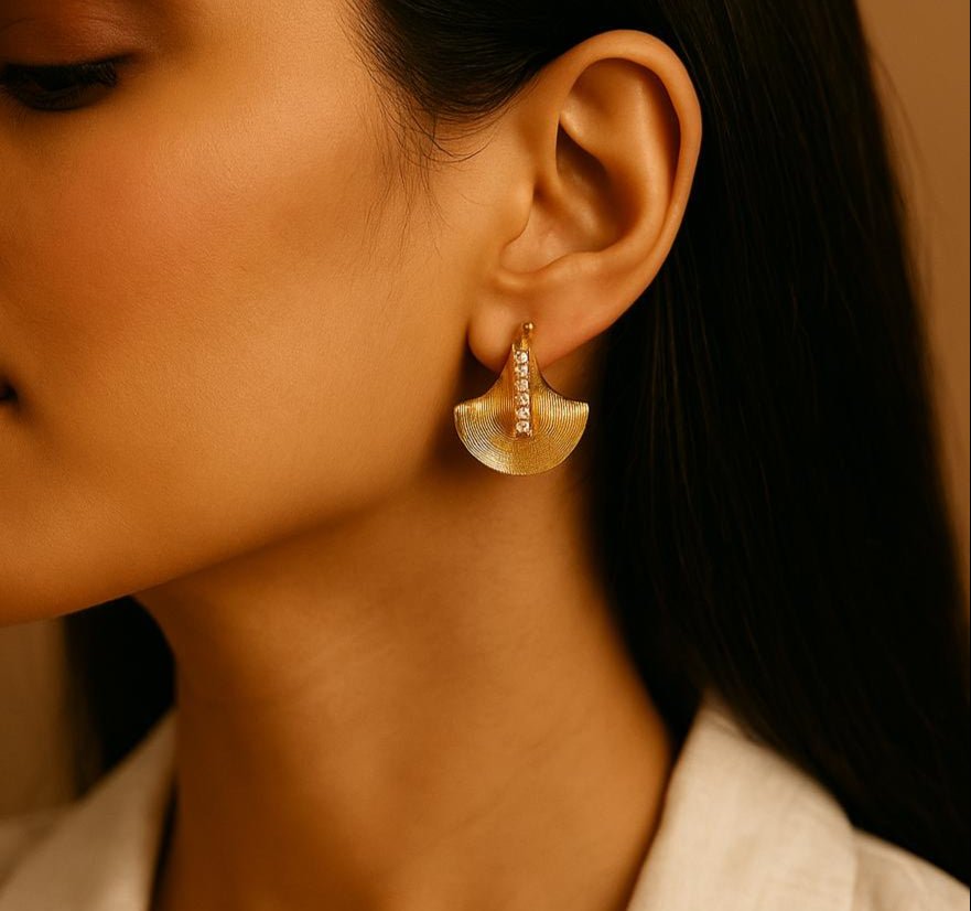 Close-up of a woman wearing gold earrings with a neutral background