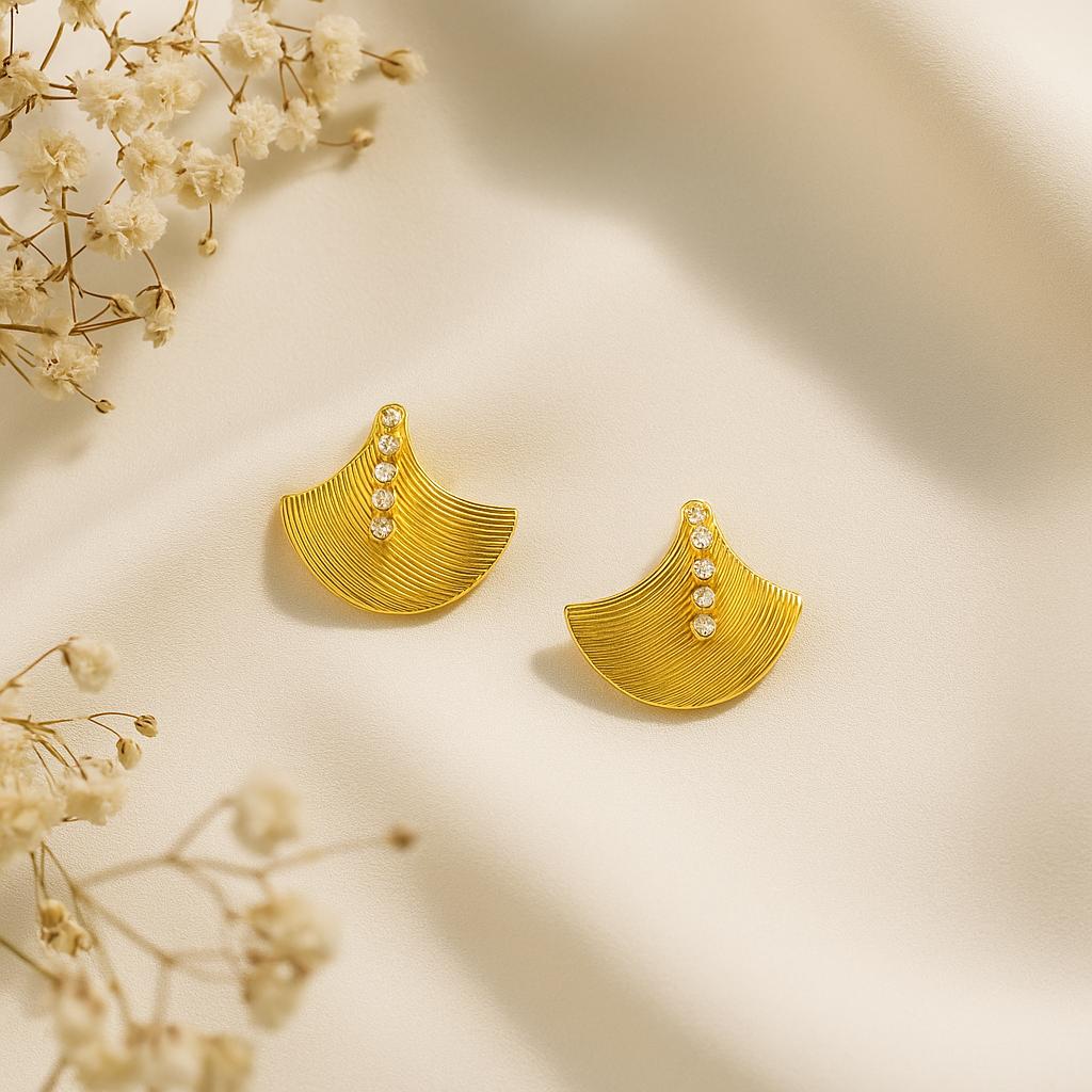 Gold earrings with small diamonds on a beige background with delicate flowers.
