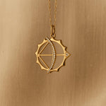 Gold pendant with diamond accents on a gold chain against a gold background
