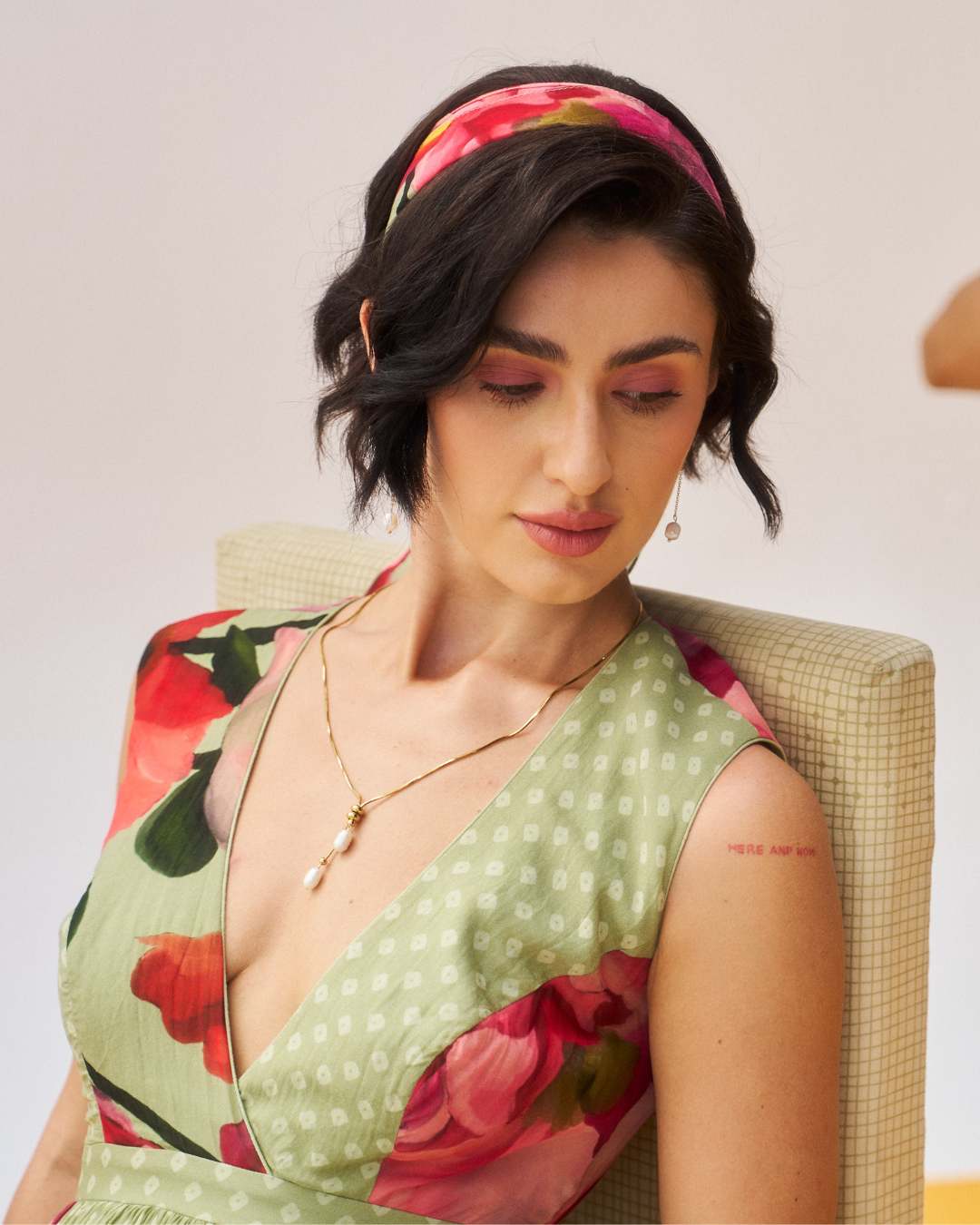 Woman wearing a green floral dress with a neutral background