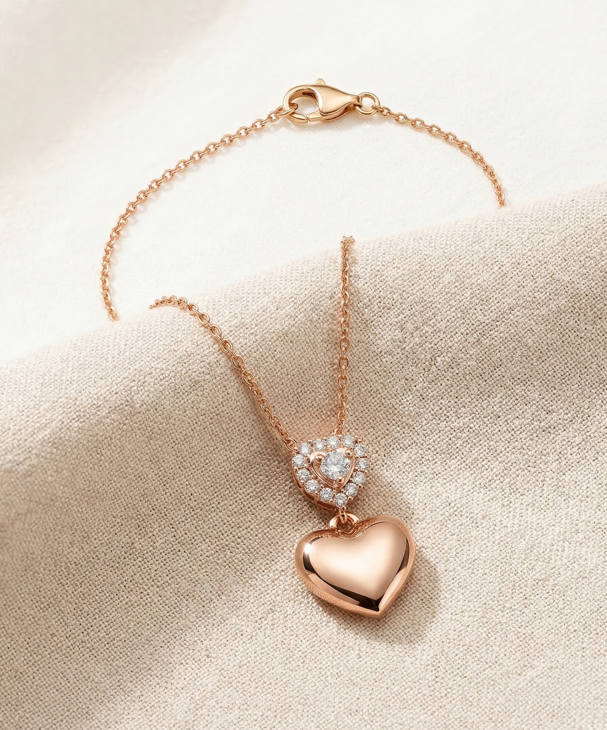 Rose gold heart-shaped necklace with a diamond pendant on a beige fabric background