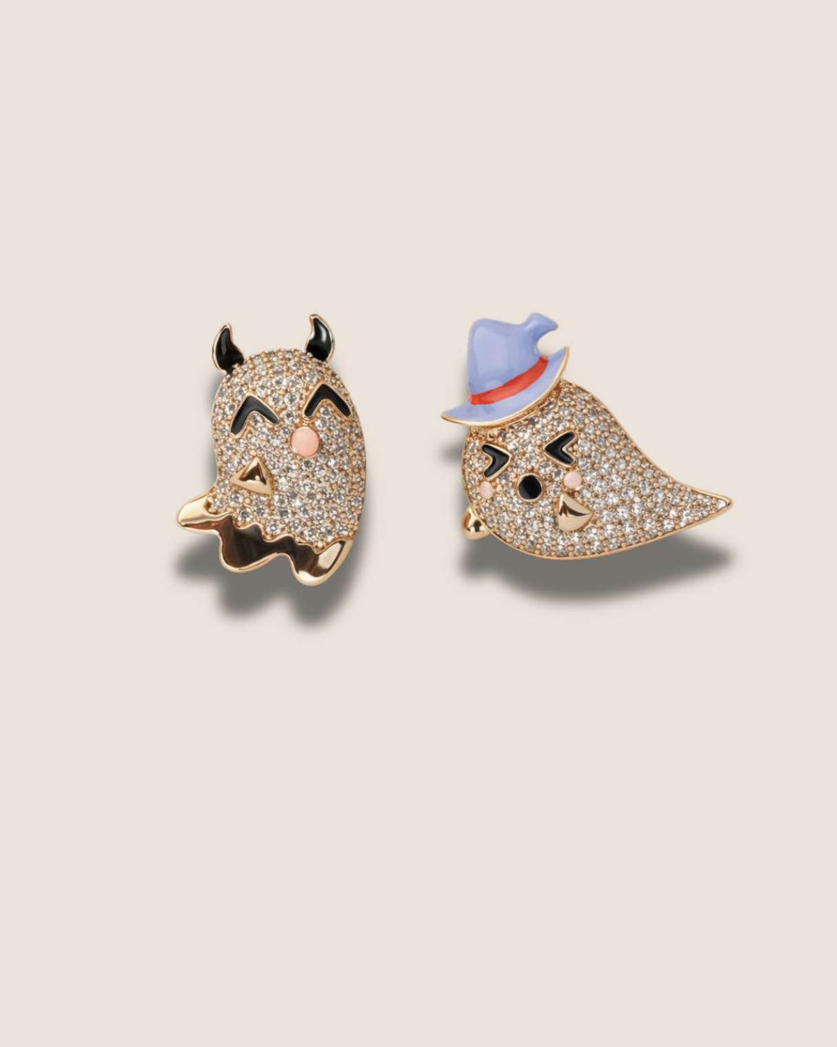 Two decorative pins, one with a devil face and the other with a bird face, on a beige background.