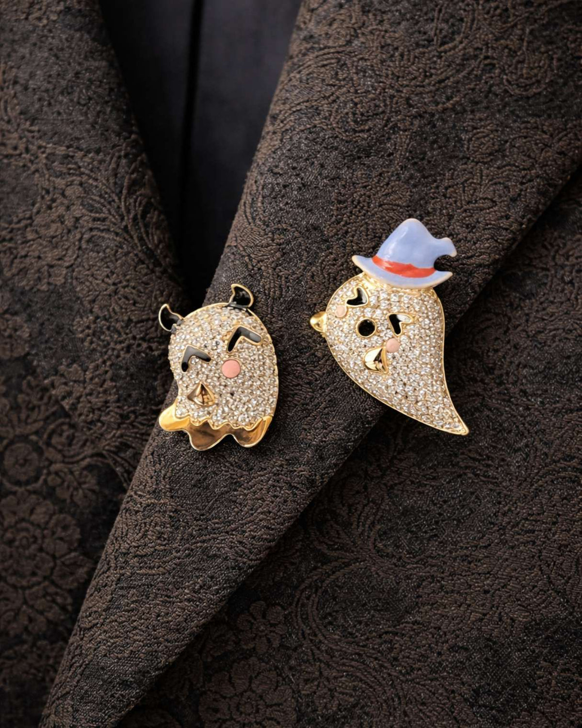 Two decorative ghost pins on a textured dark fabric background