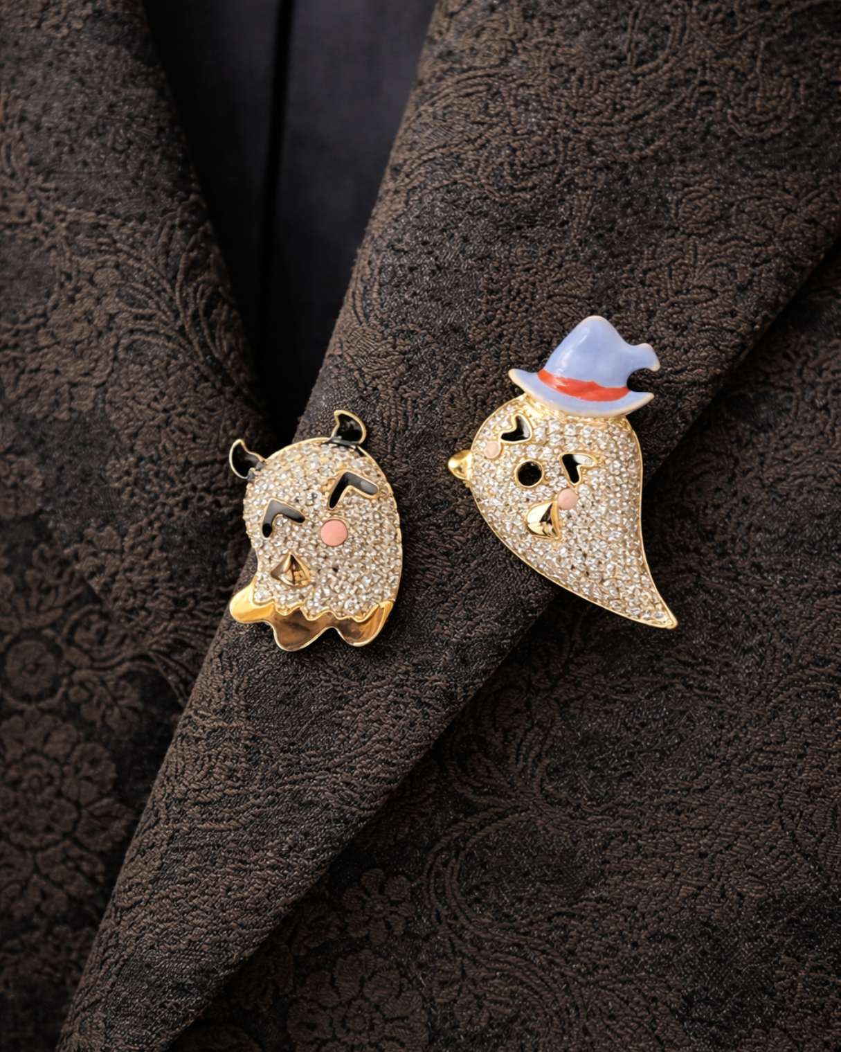 Two decorative ghost pins on a textured dark fabric background