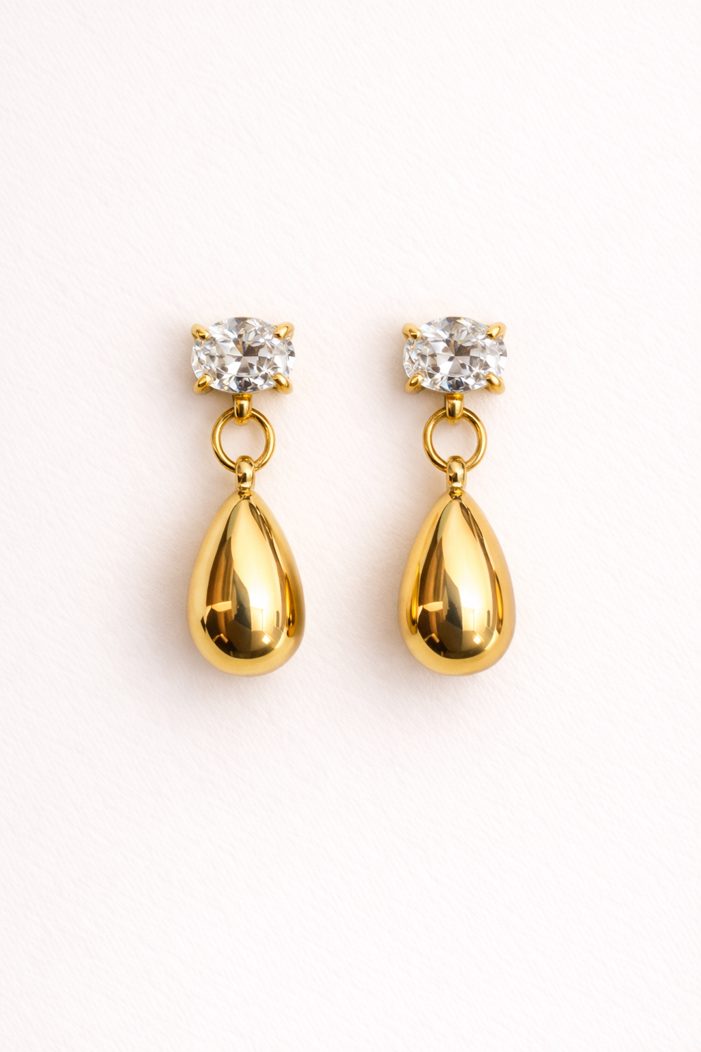 Gold teardrop earrings with clear gemstones on a white background