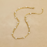 Gold necklace with pearls on a beige fabric background