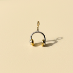 Gold and silver headphone-shaped charm on a beige background