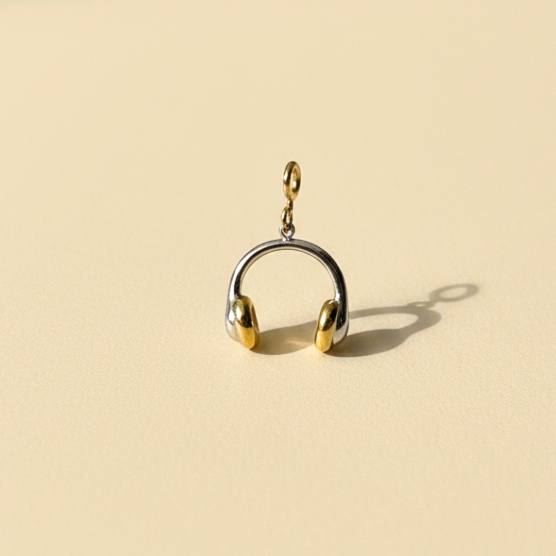 Gold and silver headphone-shaped charm on a beige background