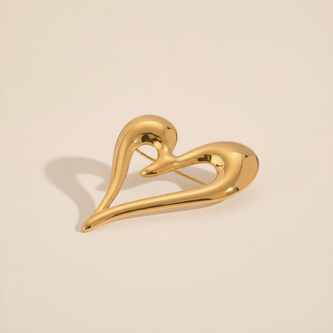 Gold heart-shaped brooch with measurements on a beige background
