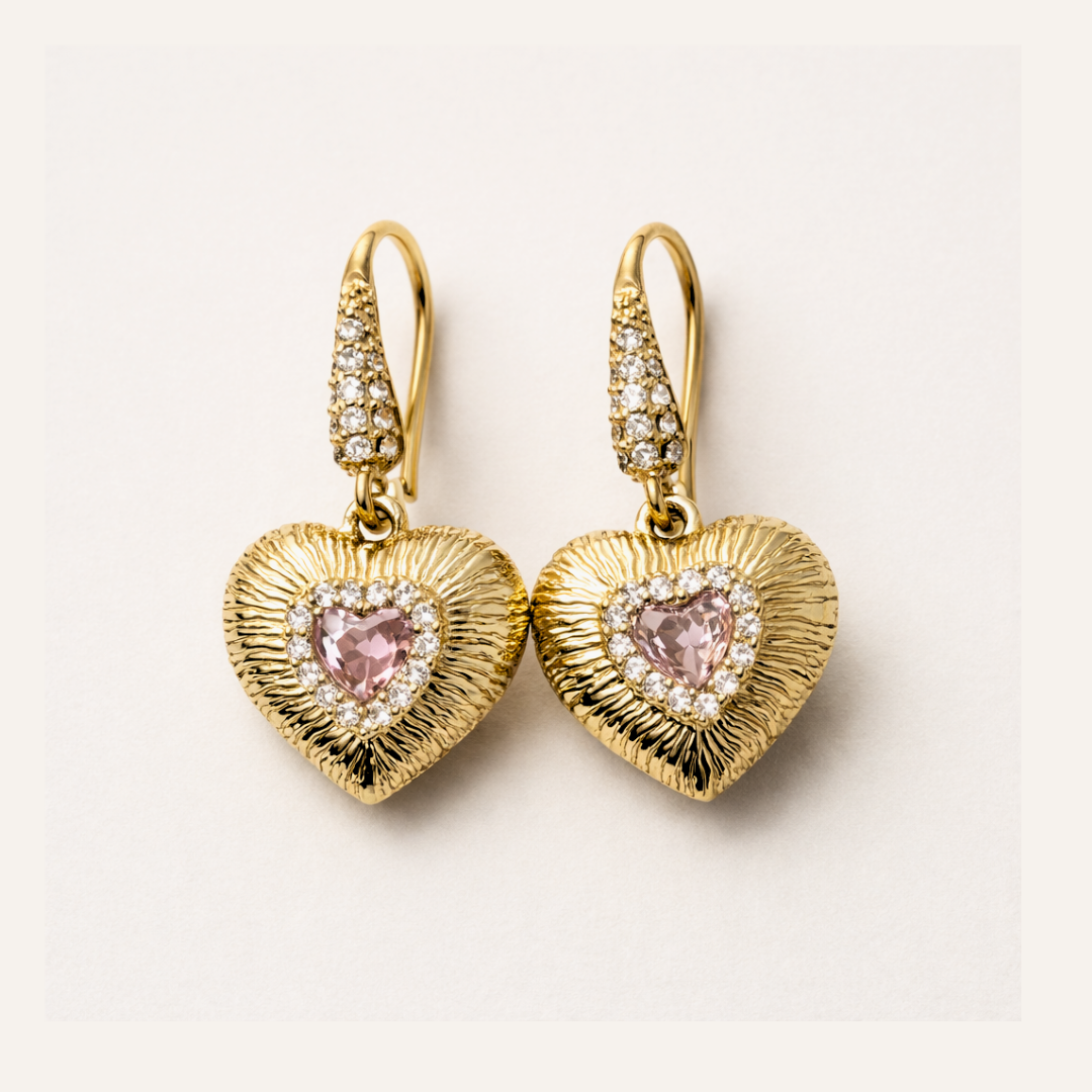 Gold heart-shaped earrings with pink gemstones on a light background
